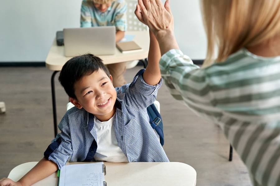 GOALS Teacher high fives little asian boy student