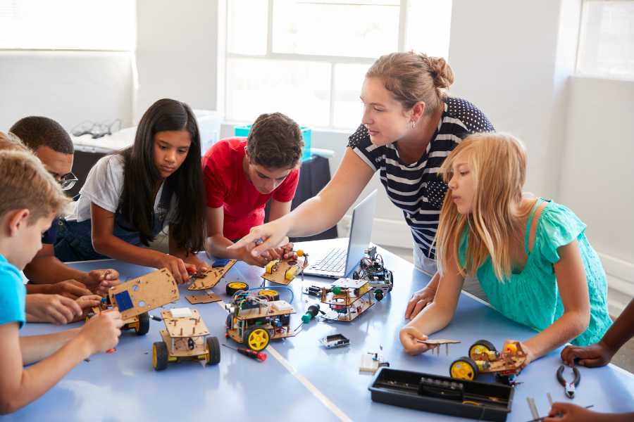 Emotional-900×600 (1) Teacher helping robotics students