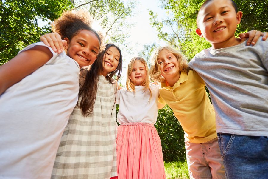 Diverse kids standing in a line with their arms around one another