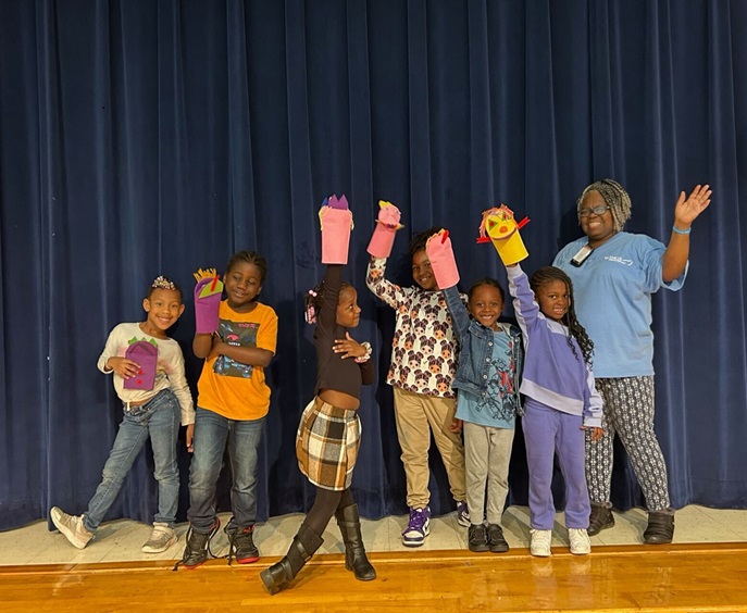 Kids on a stage holding their homemade puppets