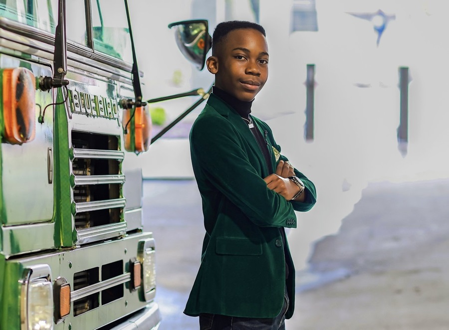 Caden Harris stands in front of his bus