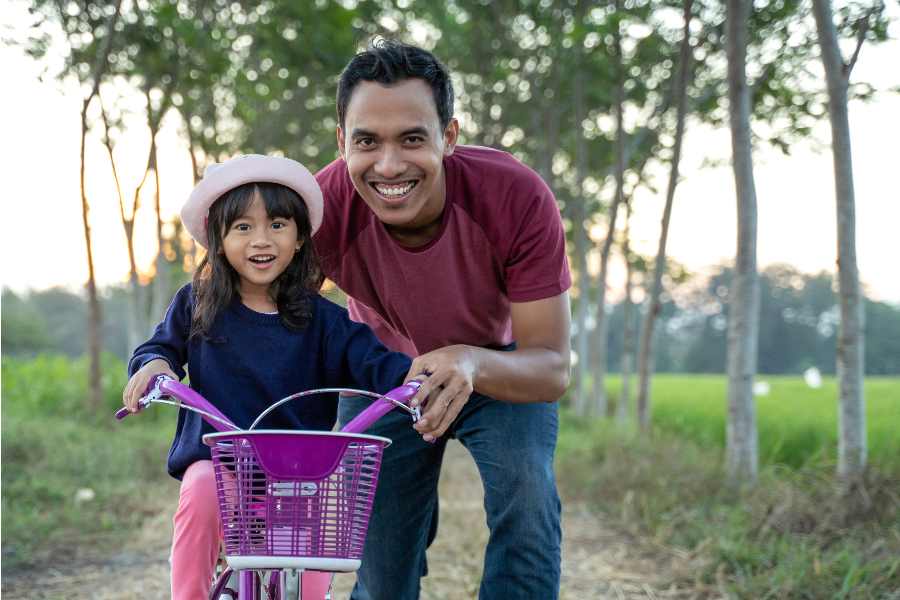 Resiliency Man teaches girl how to ride a bike